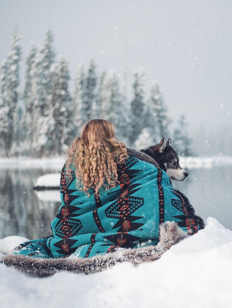 Female Model and Dog Wrapped in Faux Fur Throw Sitting in the Snow by Lake