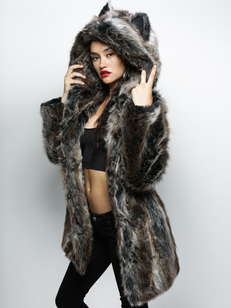 Woman wearing a furry hooded coat with her hands holding the hood.